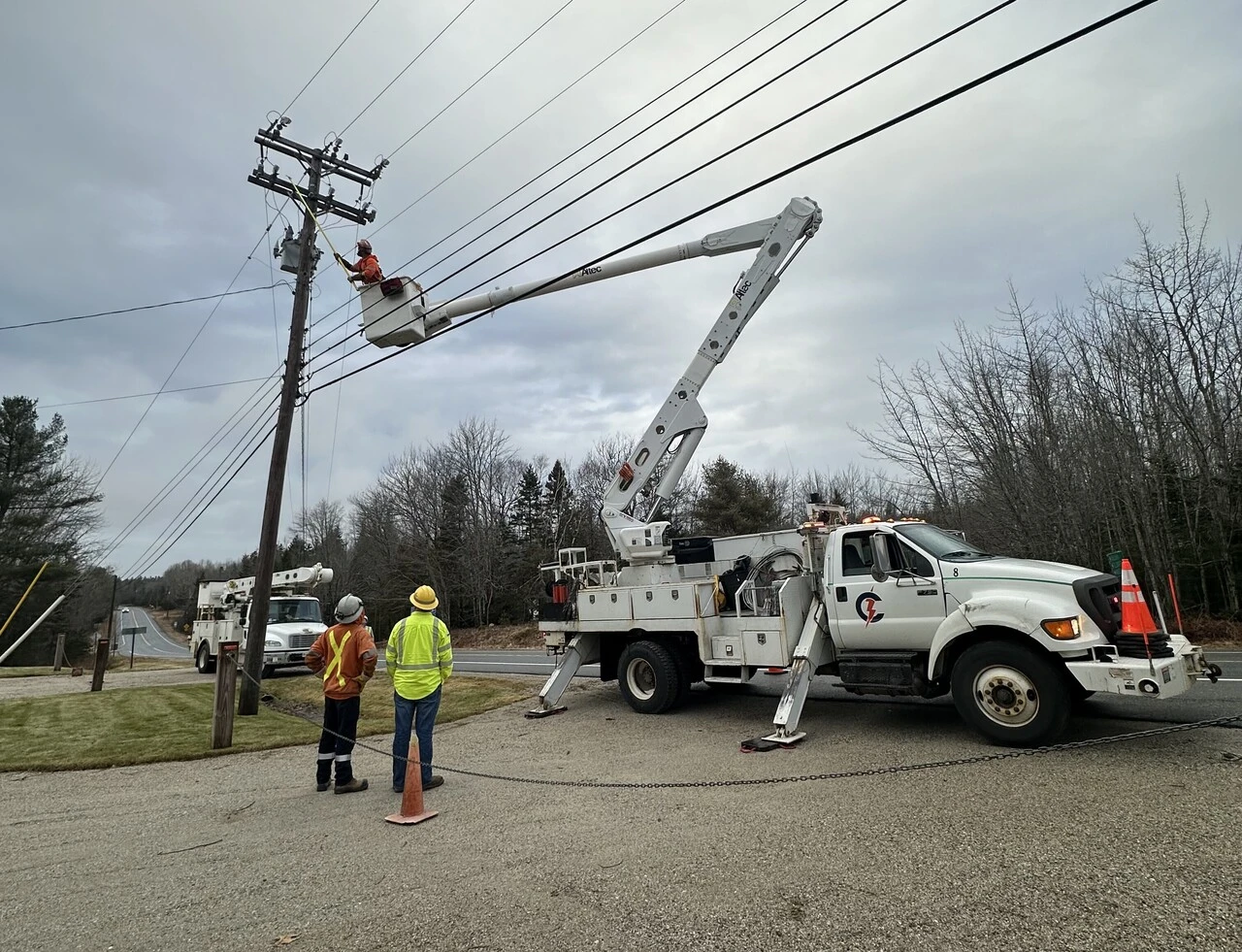 A utility truck is being worked on by two men.